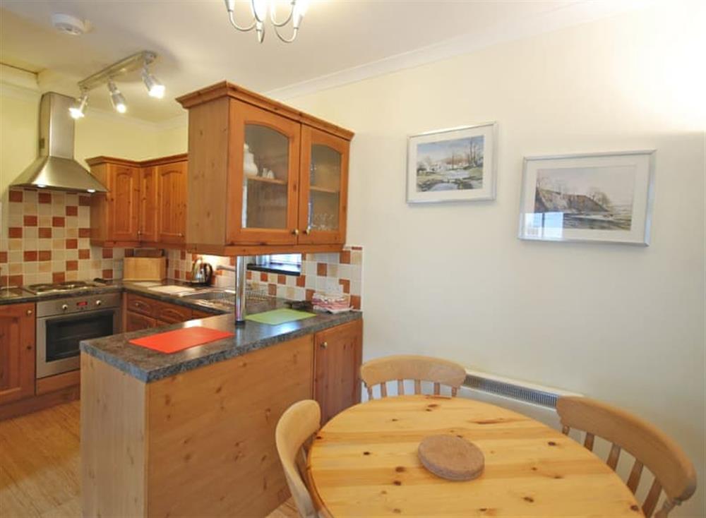 Fully equipped kitchen with dining area within the open-plan design at Clematis Cottage, 