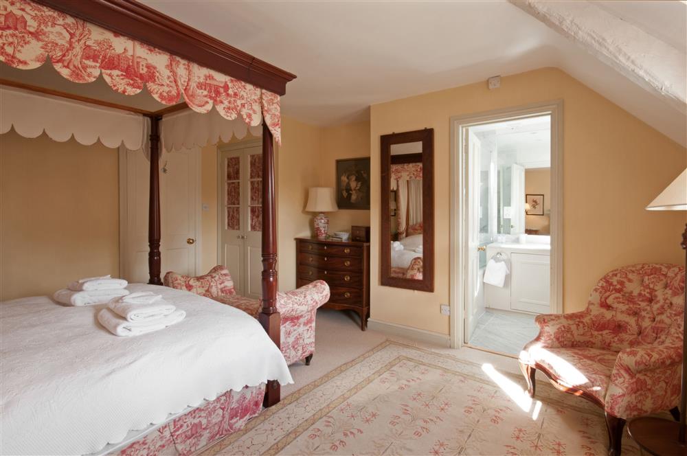 Bedroom one with its four-poster bed and en-suite bathroom at Bookers Cottage, Bruern, near Chipping Norton