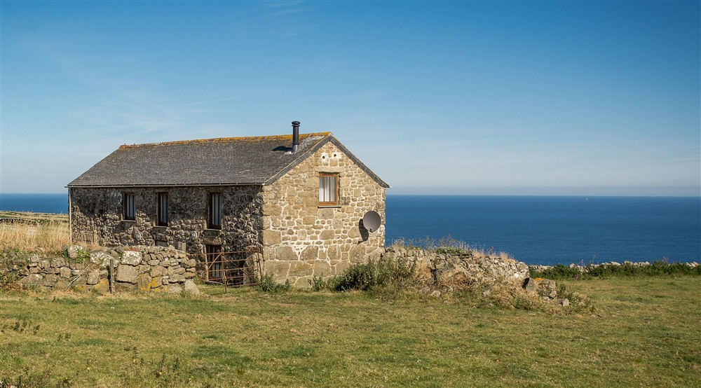 Bosigran Cottage with a field in the foreground and the sea in the background, Cornwall at Bosigran Cottage in Penzance, Cornwall