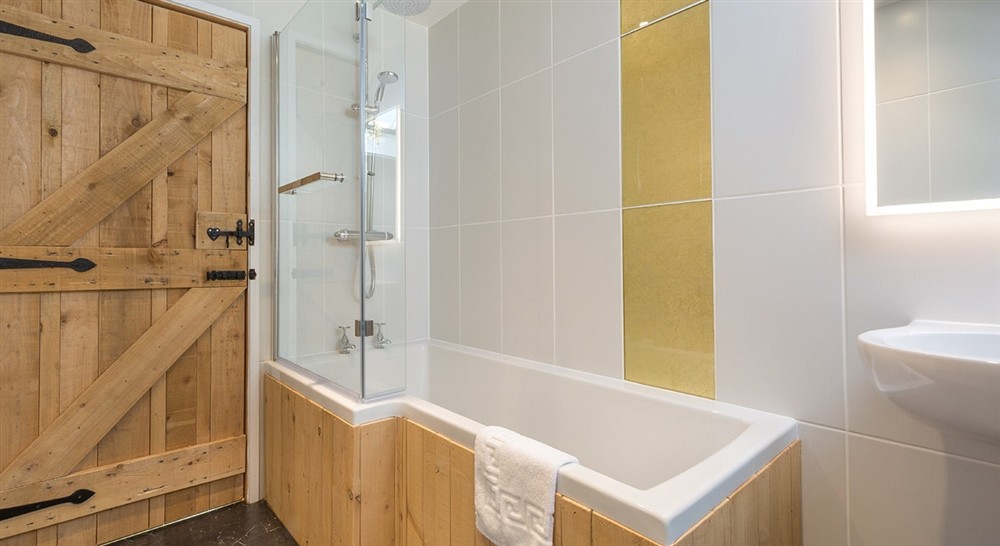 The double bedrooms en-suite bathroom, with shower over bath, at Bosigran Cottage in Penzance, Cornwall