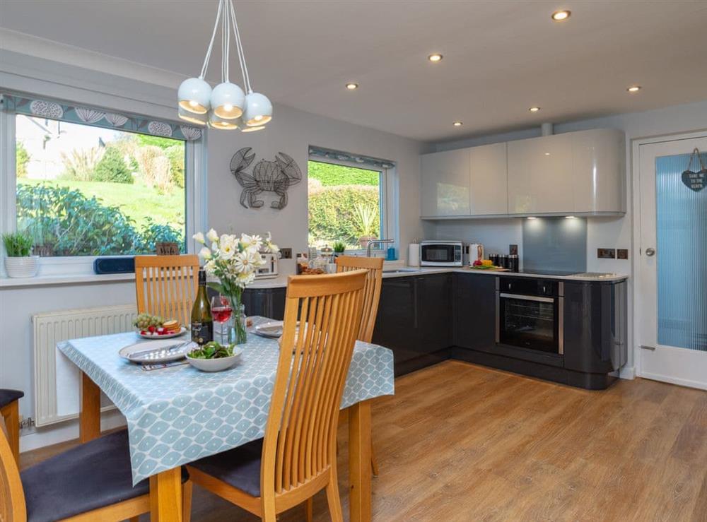 Fully equipped kitchen with dining area within the open-plan design at Bosula in Fowey, Cornwall