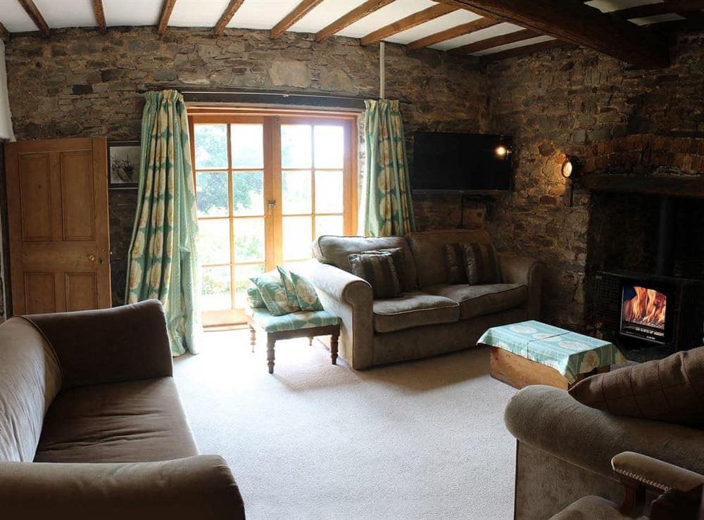 Comfortable living room with wood burner and exposed stone walls at Boundstone Farmhouse in Littleham, near Bideford, Devon