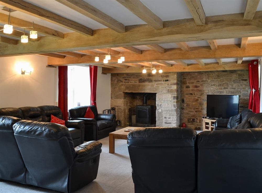 Living room with beamed ceiling & wood burner at The Farmhouse, 