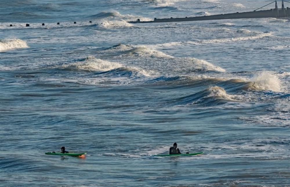 Surfers at high tide at Boycott House, Cromer