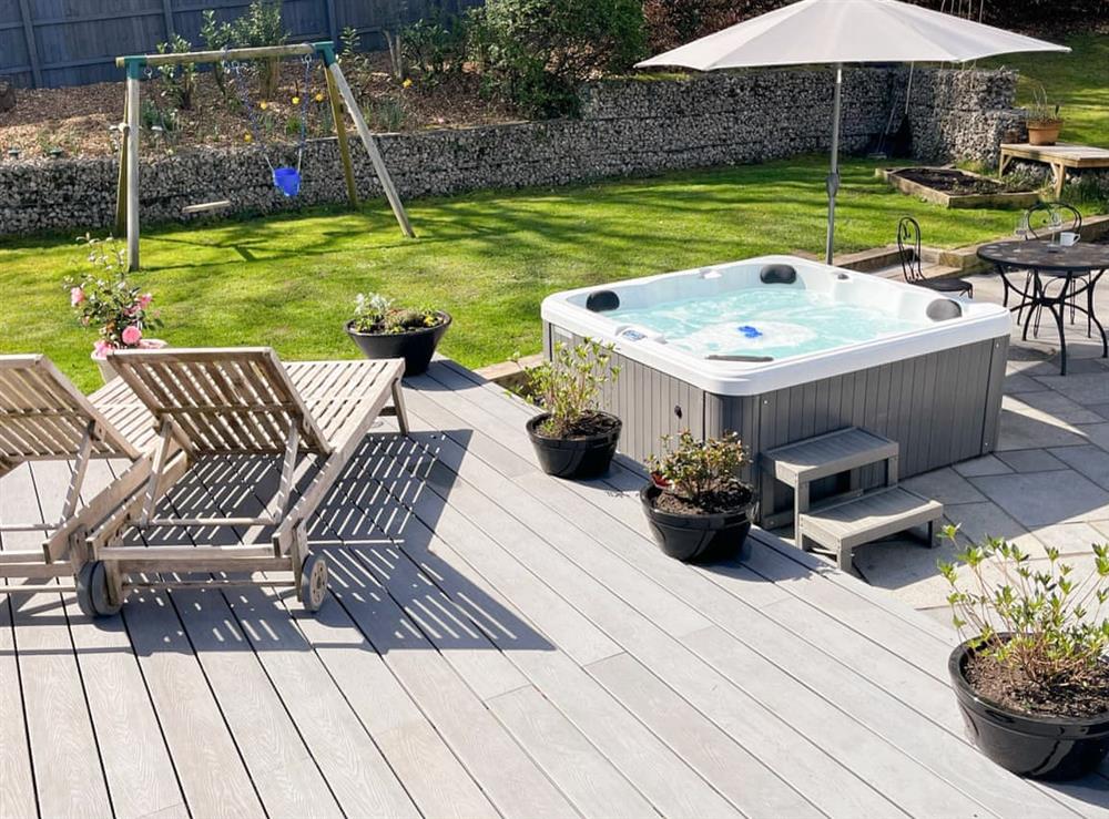 Patio with hot tub, sun loungers and garden swing at Brackenwood in Caldy, near West Kirby, Merseyside