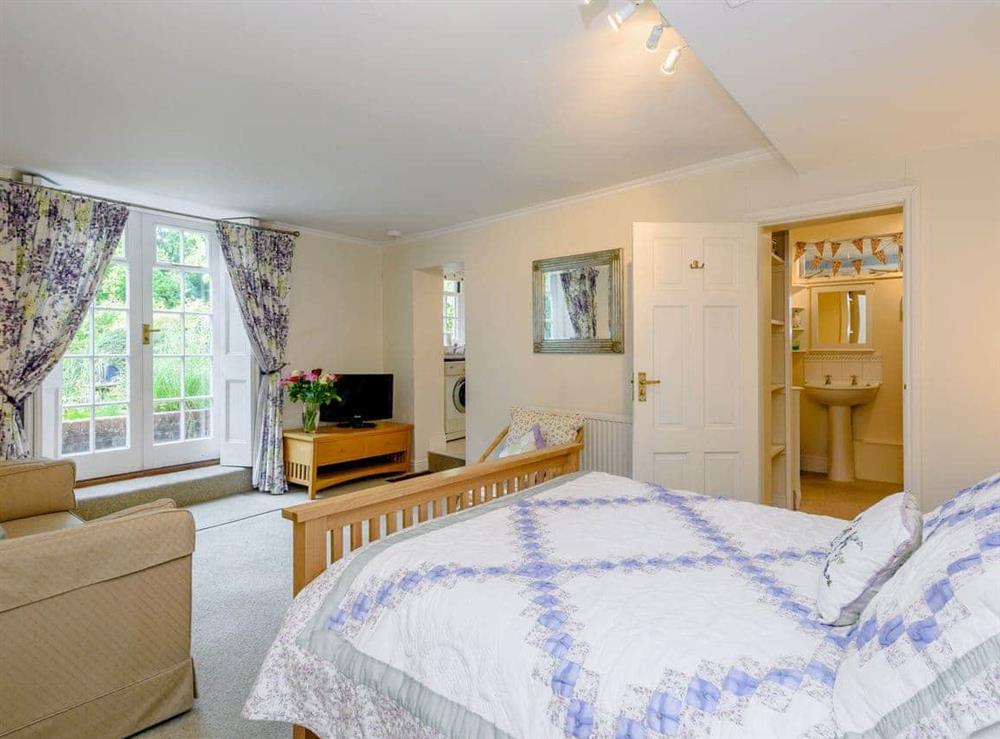 Bedroom with, Freeview TV, sitting area, kitchenette, French doors leading to garden, and en-suite with shower over bath, and toilet at Braydeston House in Brundall, near Norwich, Norfolk