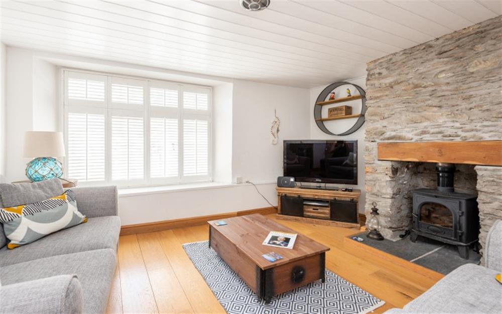 The lounge with wood stove and wide window seats at Bridgend House in Polperro
