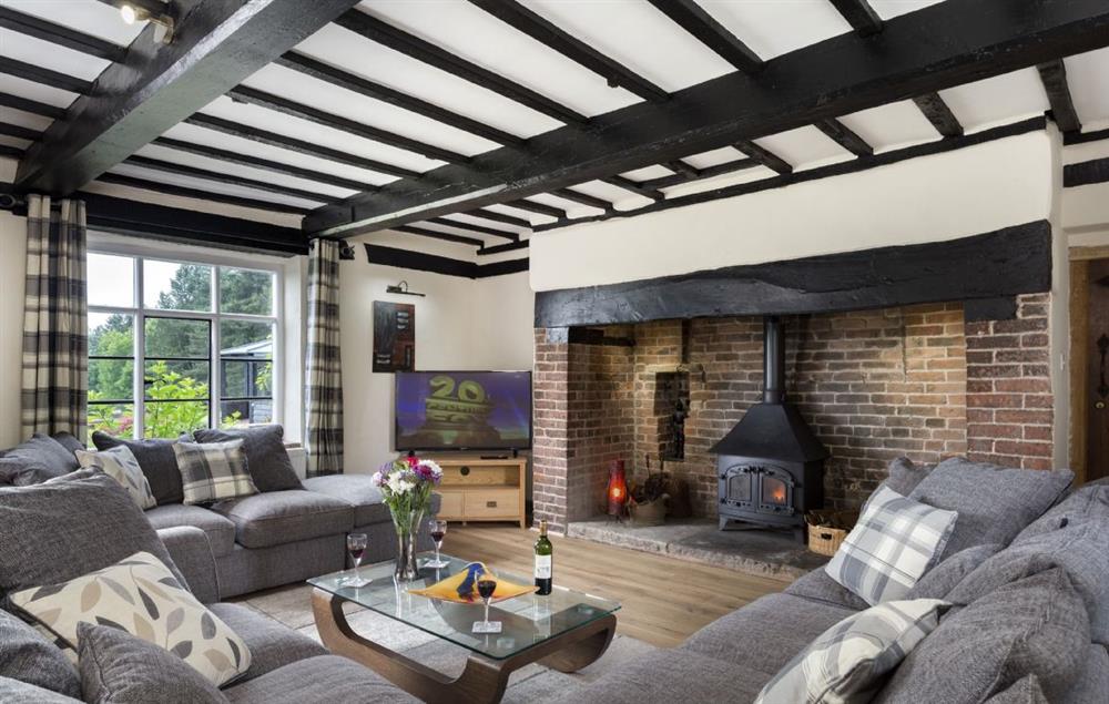 Spacious sitting room with inglenook fireplace and wood burning stove at Broad Meadows Farmhouse, Bayton