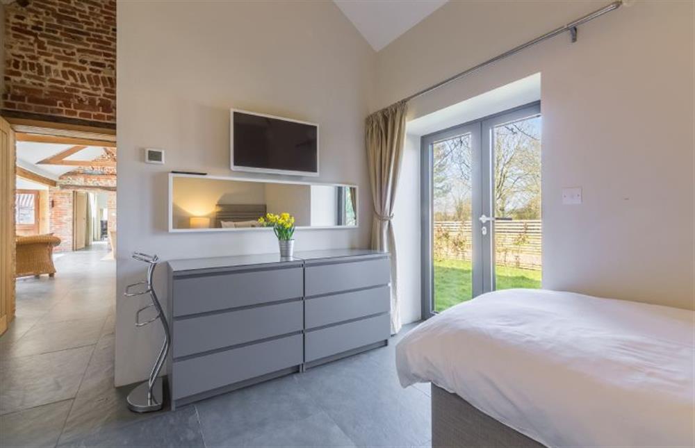 Ground floor:  Bedroom two with flat screen television and door to front garden at Bromholm Barn, Ridlington near Norwich