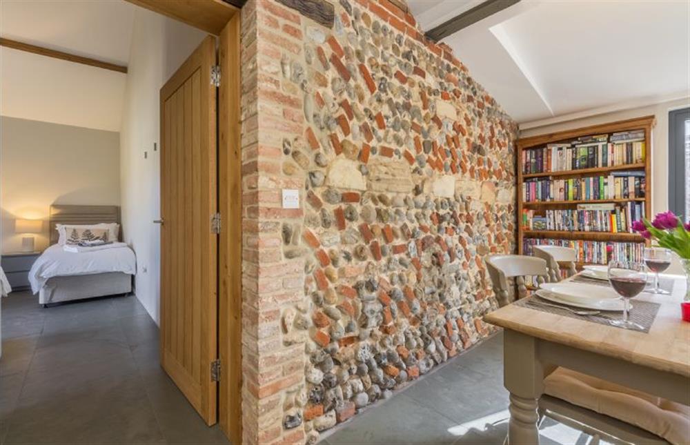 Ground floor:  Feature brick wall and bookcase, door to bedroom two at Bromholm Barn, Ridlington near Norwich
