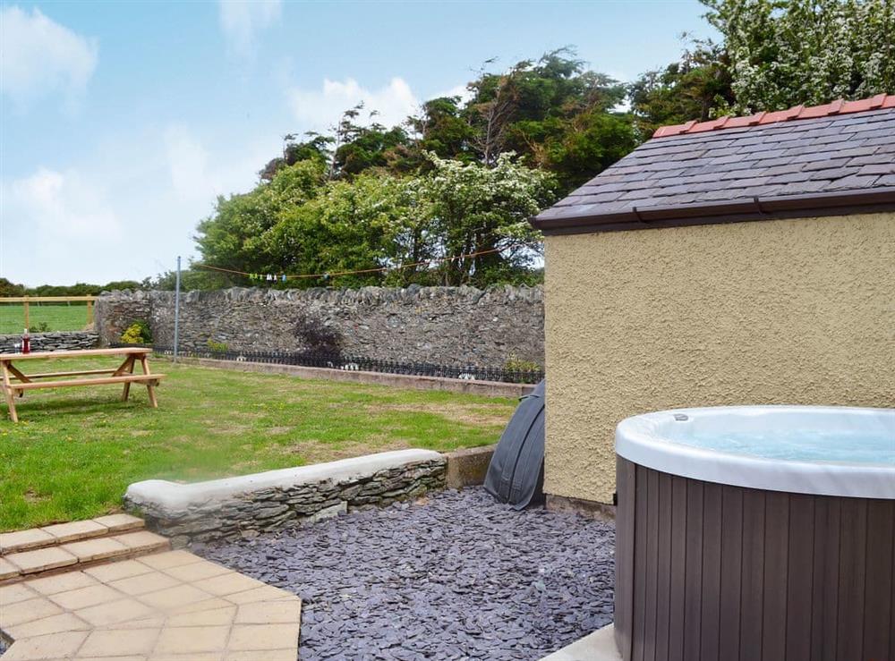 Enclosed lawned garden with sitting-out area, garden furniture and private hot tub at Yr Hen Stabal, 