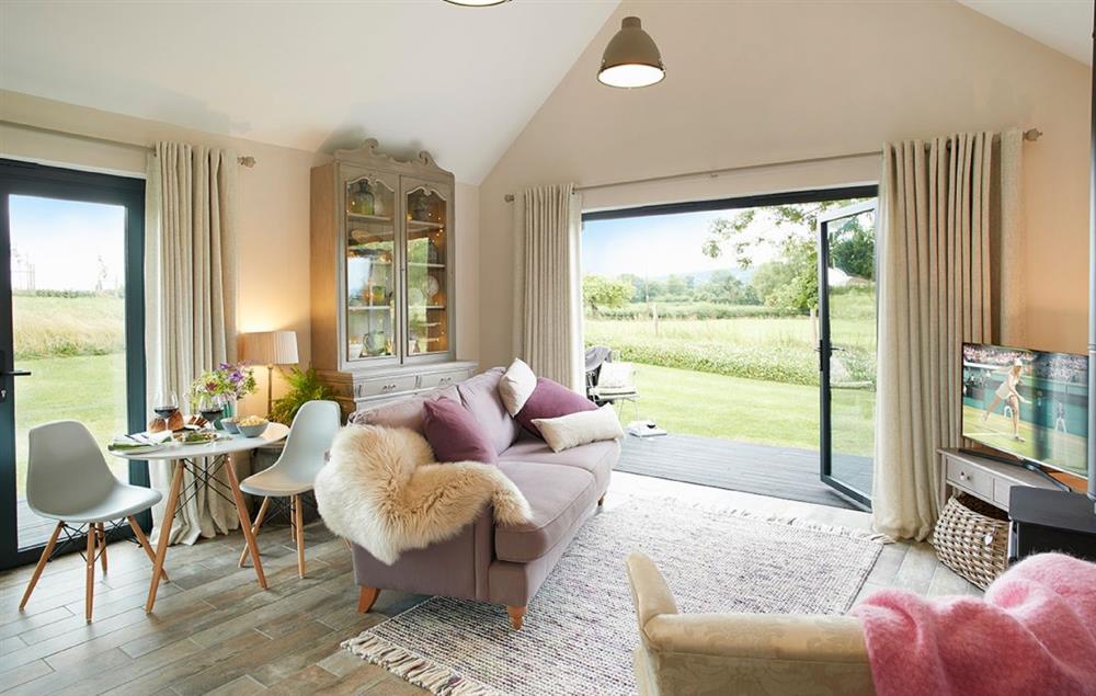 Open plan kitchen/dining/living area with bi-fold doors opening to private decked area at Broomers Barn, Ludlow