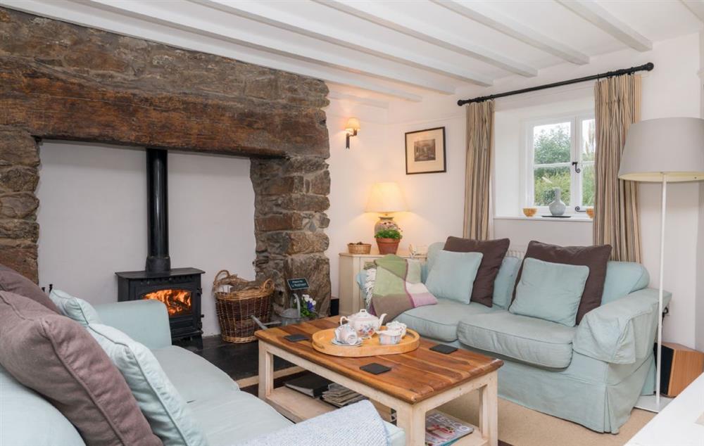 Sitting room with beamed fireplace and multi fuel burning stove at Bryn Rhydd, Bodnant Estate