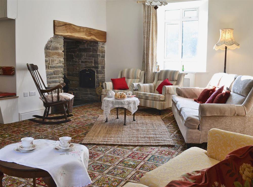 Large living room with wood-burning stove in inglenook fireplace and games area at Brynog Mansion Farmhouse in Lampeter, near Aberaeron, Dyfed