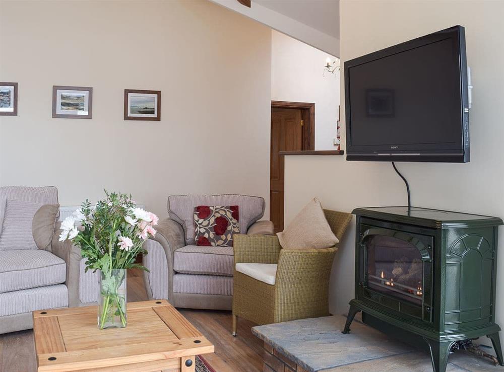 Living room with gas log burner & wall mounted TV at Brynymor Cottage in Llangennith, near Swansea, Glamorgan, West Glamorgan