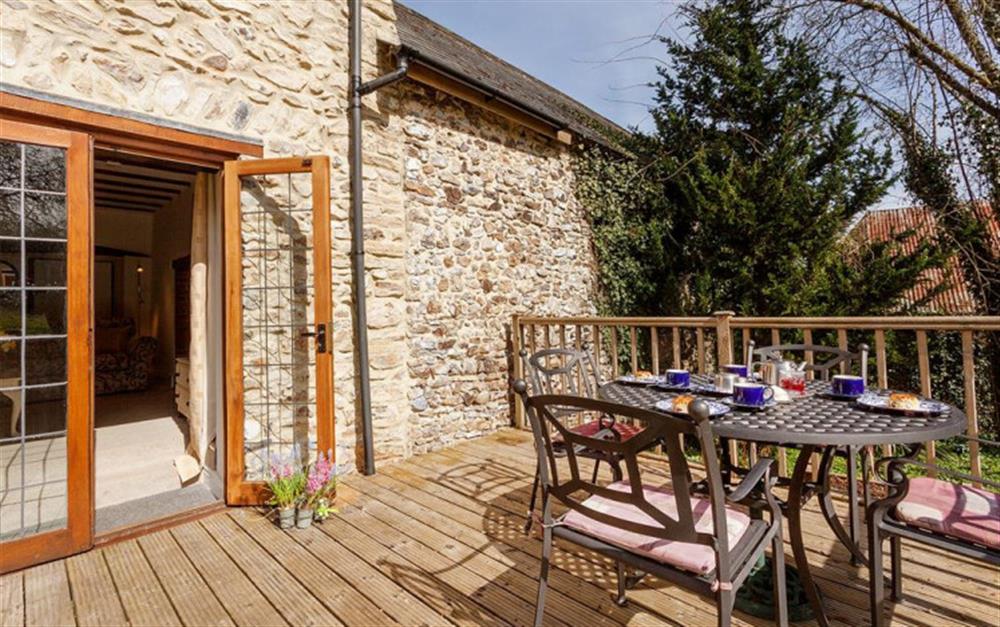 Outdoor deck with table and chairs for dining at Burrow Hill Cottage in Honiton
