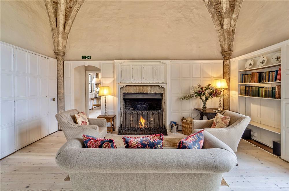 Drawing room with open fire and plenty of books at Butley Priory, Woodbridge