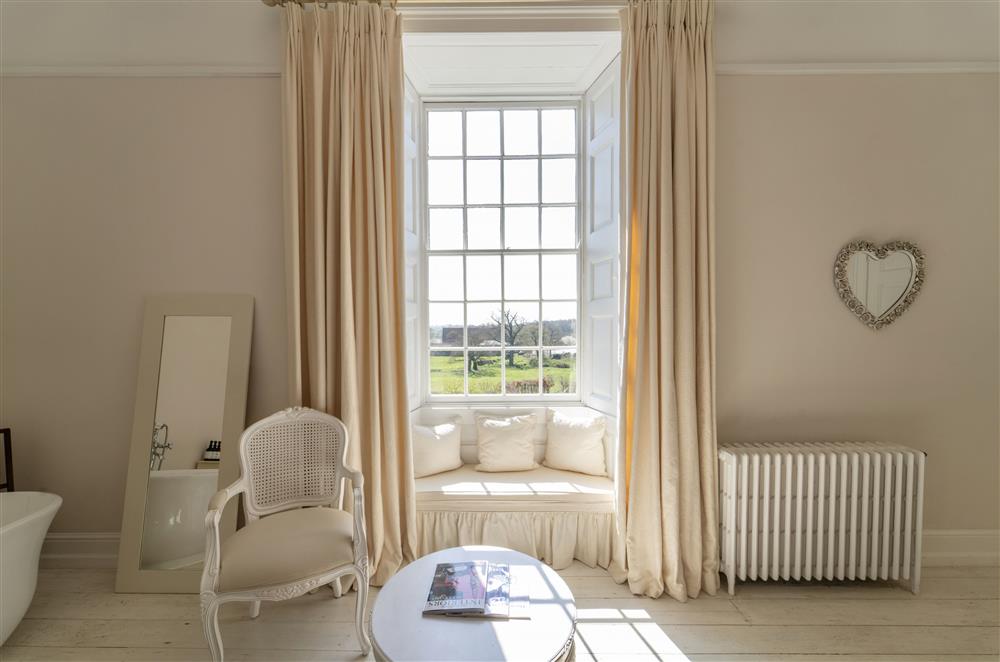 Window seating, luxurious seating and a free standing bath in one of the bedrooms at Butley Priory, Woodbridge