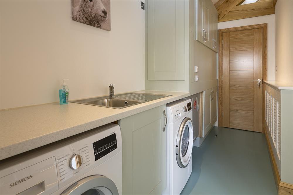 Utility/cloakroom is equipped with a washing machine, tumble dryer and small sink at Butterwell Barn in , Nr Dartmouth