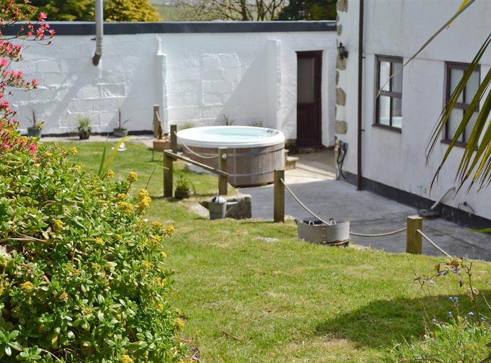 Rear garden with courtyard containing a hot tub at The Farmhouse, 