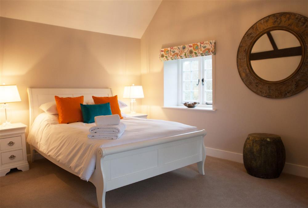 Hummingbird bedroom with a 5’ king-size bed and television at Calcot Farmhouse, Montgomery