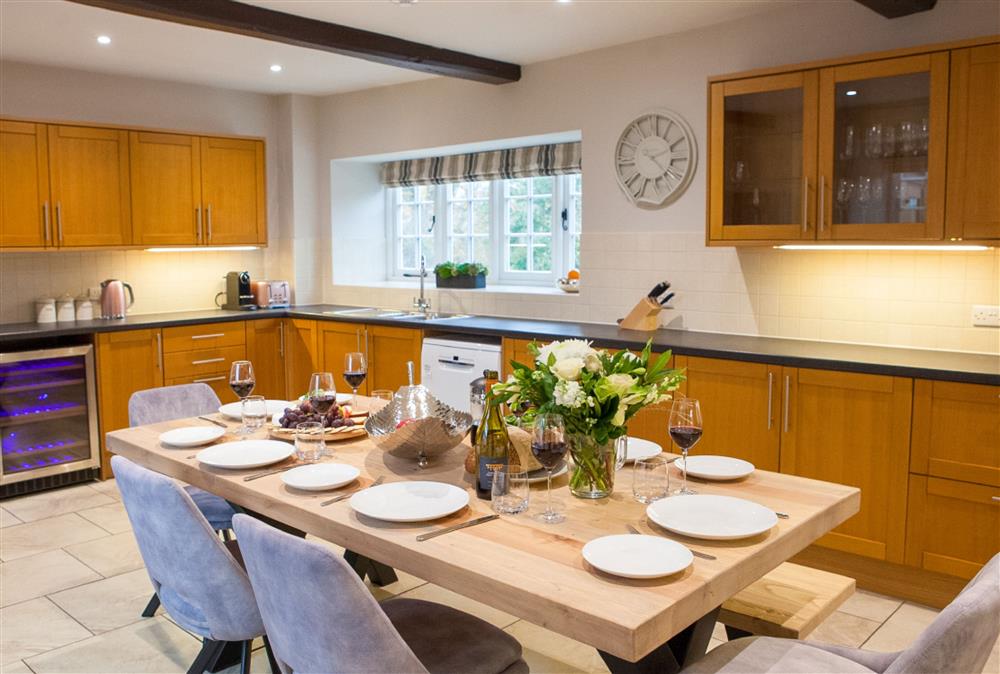Kitchen/dining room with wine fridge and dining table seating eight guests at Calcot Farmhouse, Montgomery