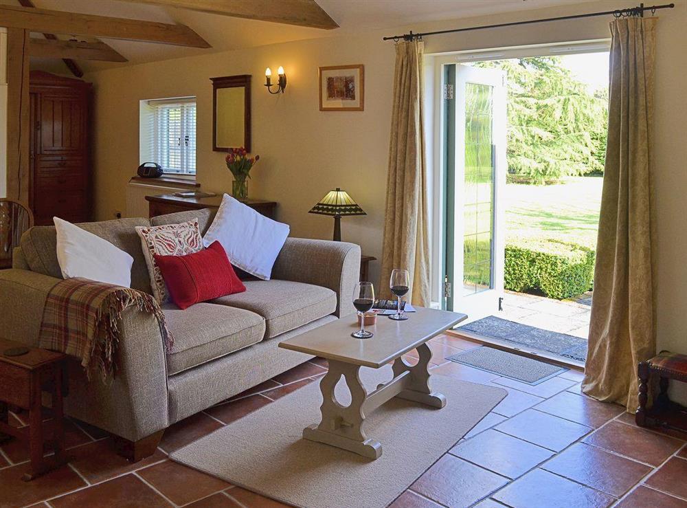 The tile floor complements the exposed beams and the living room opens directly onto the garden at The Stables, 