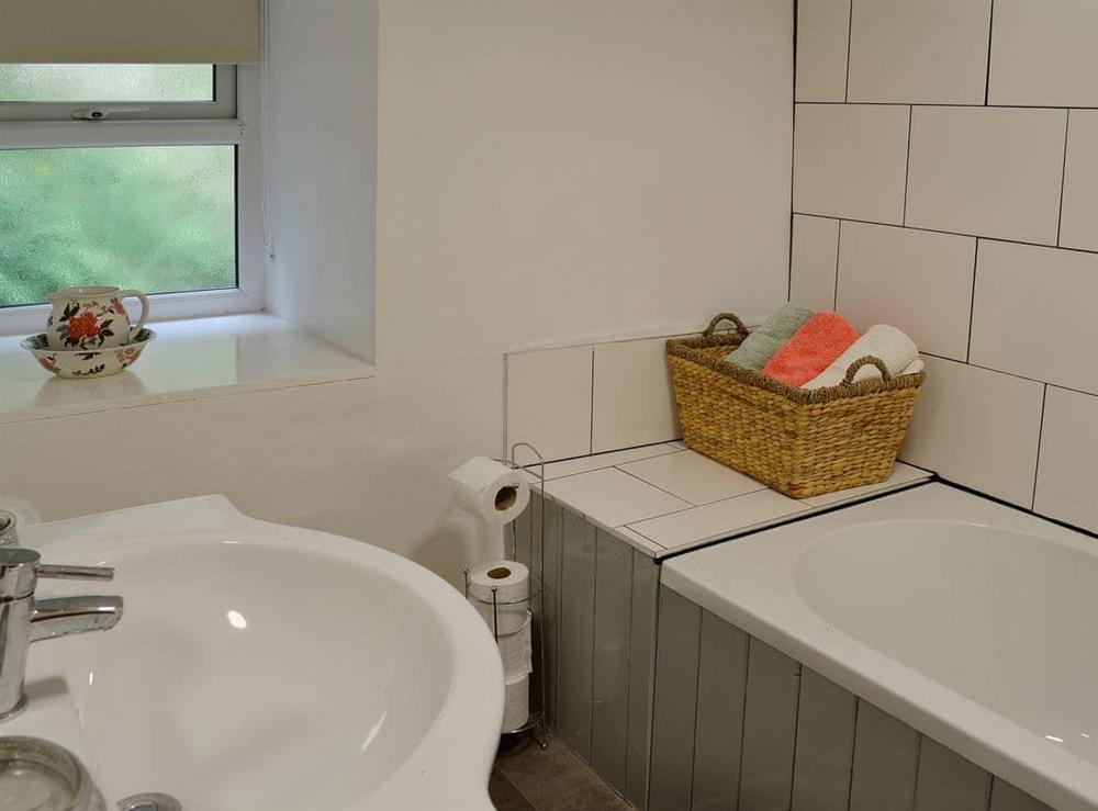 Family bathroom with contemporary tiling and shower over the bath at Capel Fawnog Mawr in Talsarnau, Gwynedd