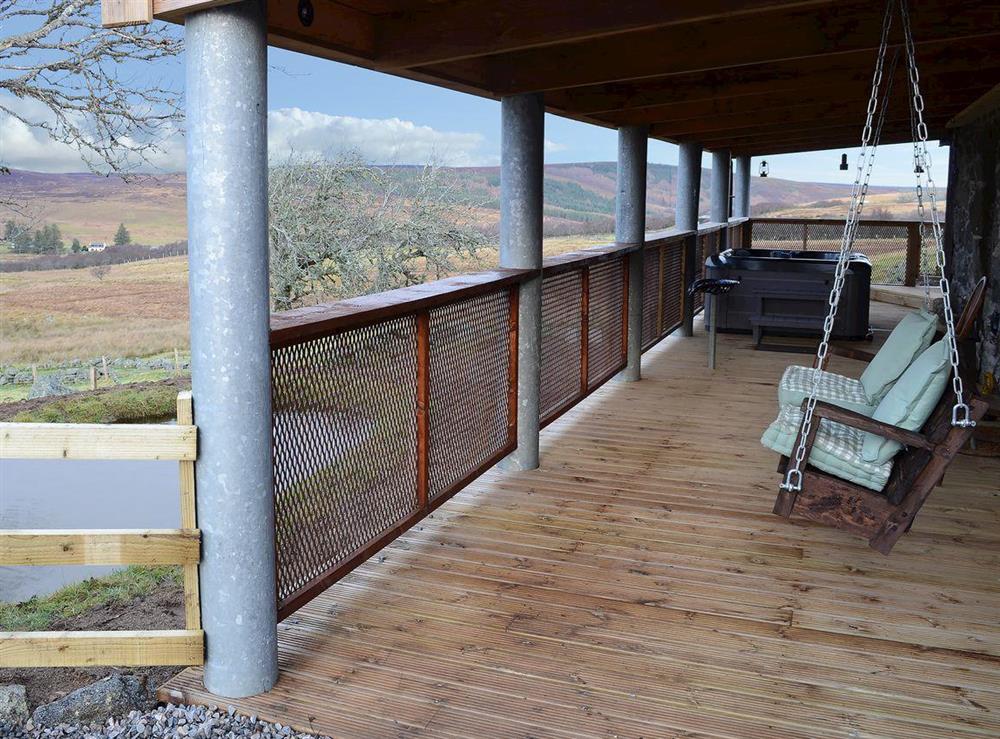 Wooden covered veranda with seating and hot tub at Capercaillie Cottage in Rhilochan, Rogart, near Dornoch, Highlands, Sutherland