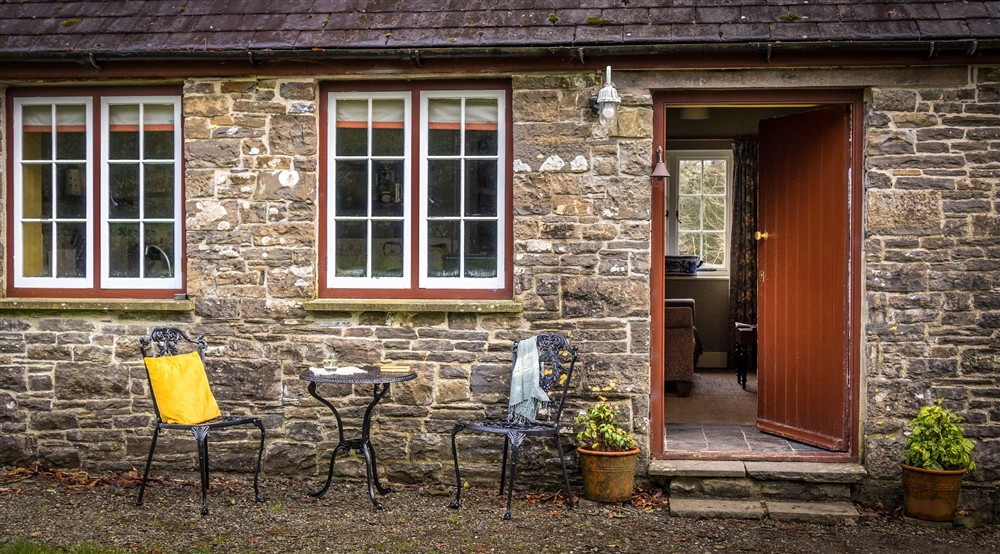 The exterior of Cariad Cottage, with outdoor dining furniture on the gravel by the entrance to the cottage, Carmarthenshire at Cariad Cottage in Llandeilo, Carmarthenshire