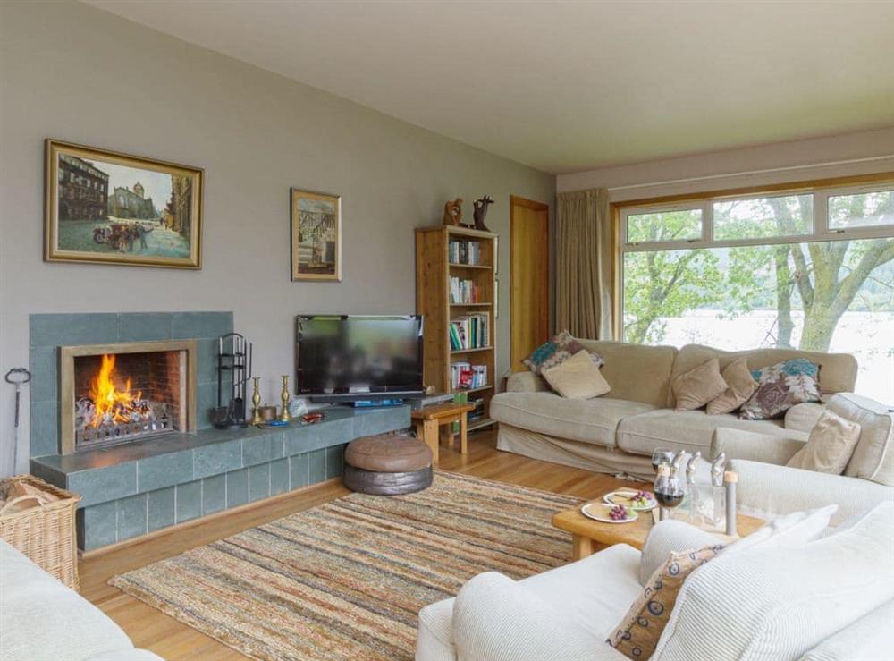 Large living room with open fire, loch views and patio doors (photo 2) at Carsaig in Brig o’Turk, near Callander, Perthshire