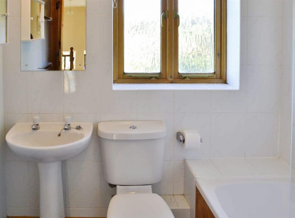 Tiled bathroom with shower over bath at Carters Cottage in Puncknowle, Dorchester., Dorset