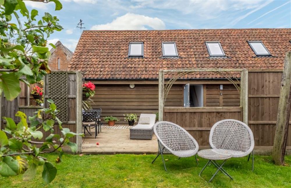 Large garden with decked area with table and chairs, sun loungers, hot tub and gas barbecue at Cartshed Lodge, Hoveton near Norwich