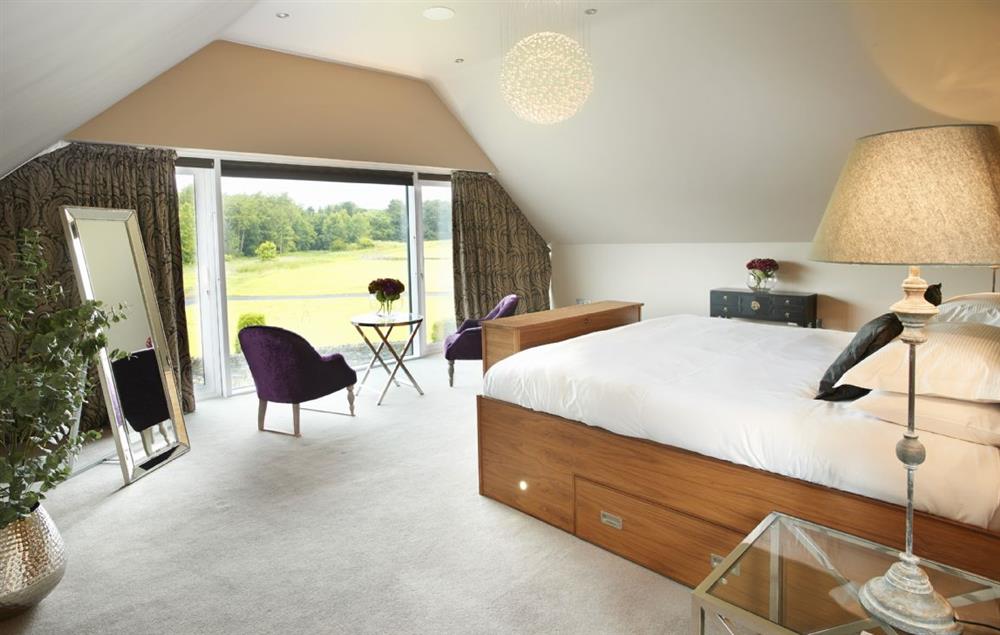 Master bedroom with emperor bed, dressing area and large windows overlooking the golf course at Carus House, Burneside