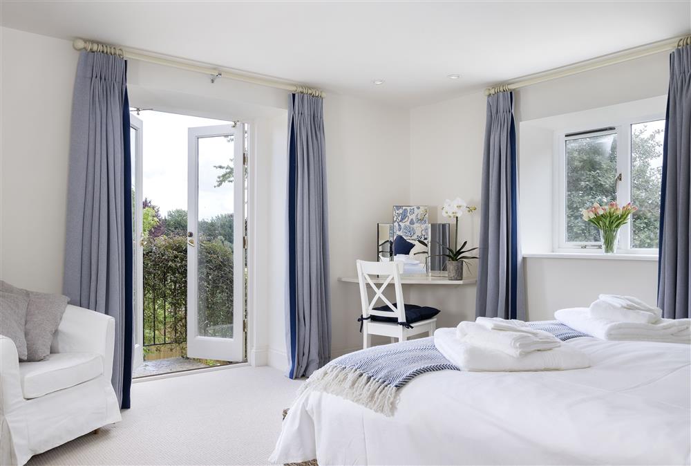 First floor: Master bedroom with french doors leading to the external stone staircase at Cats Abbey Cottage, Northleach