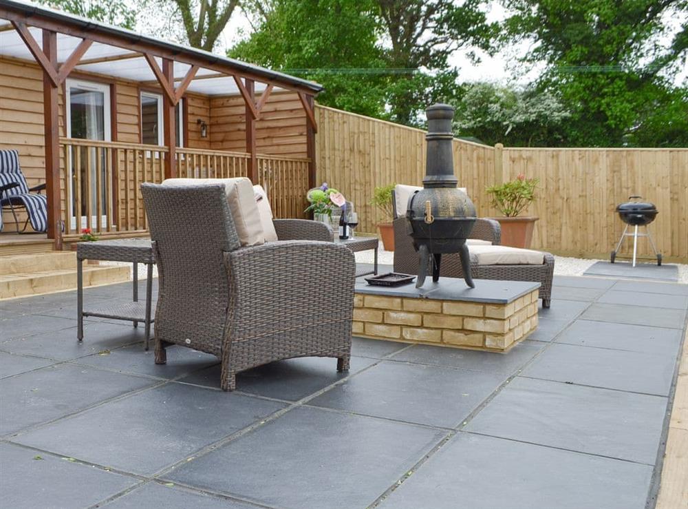 Paved patio area with outdoor furniture at Cedar Lodge in Cowbeech, near Hailsham, East Sussex
