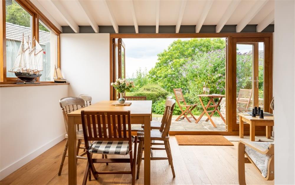 Bright open plan dining area with concertina doors to patio at Chantry Cottage in Dittisham