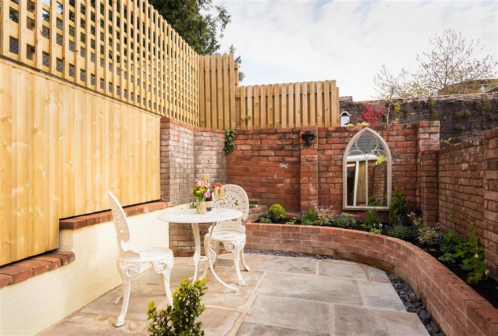 Pretty terraced rear courtyard garden with garden furniture and charcoal barbecue at Chapel Cottage,  Uffculme