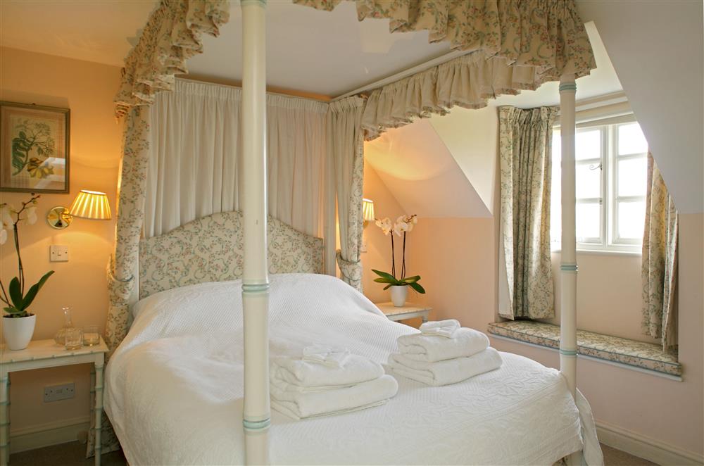 Bedroom one with a 4’6 four-poster double bed and wash basin at Cheltenham Cottage, Bruern, near Chipping Norton