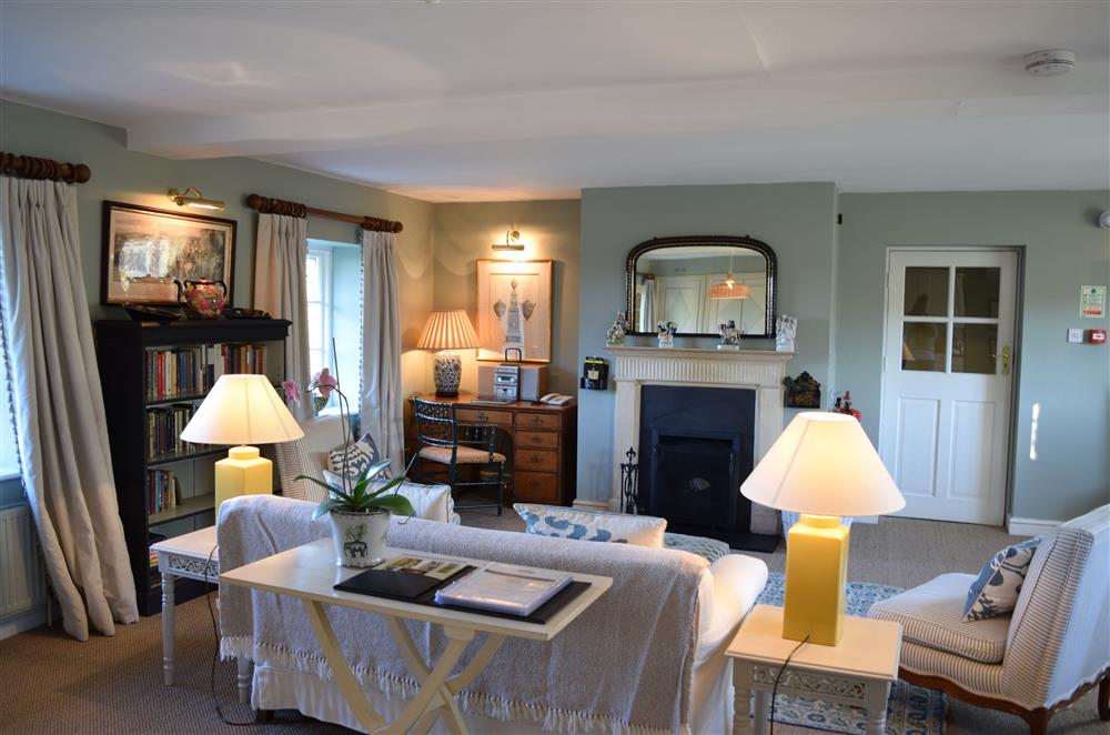 The sitting room boasts an open fire and views across the estate gardens at Cheltenham Cottage, Bruern, near Chipping Norton