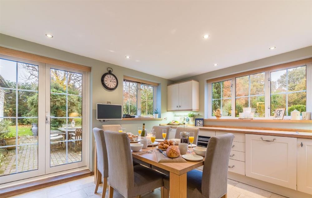 Kitchen with breakfast table and french doors which open onto a paved terrace at Cherry Cottage, Ripe