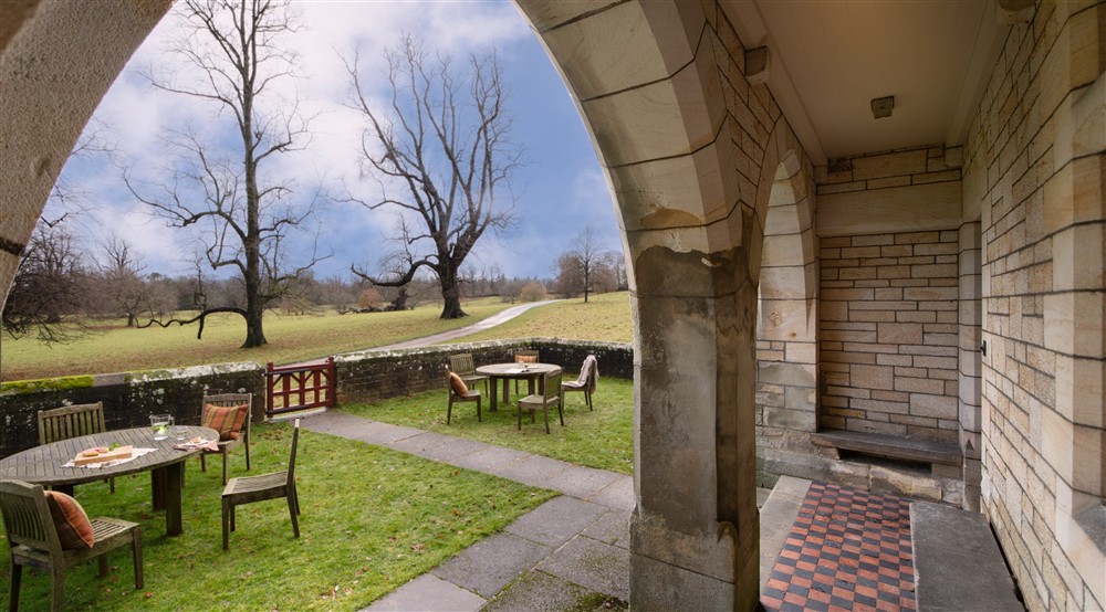 The enclosed garden with covered terrace, tables and chairs overlooks Studley Royal Deer Park at Choristers' House in Nr Ripon, North Yorkshire