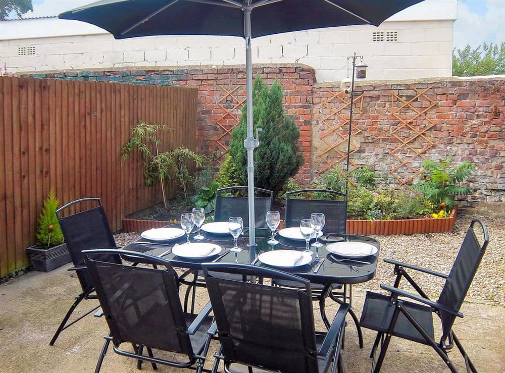 Enclosed courtyard with sitting-out area, garden furniture and barbecue at Church Court Cottage in Beeford, near Driffield, North Humberside