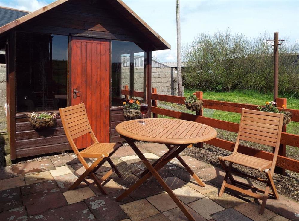 Paved patio with furniture and summerhouse at The Bothy, 