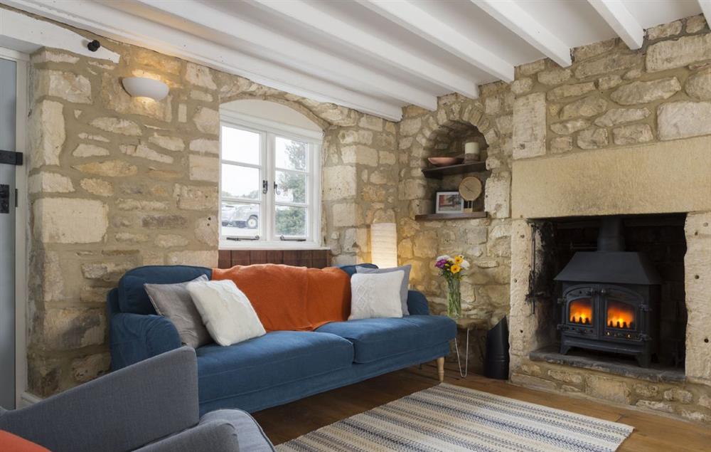 The cosy sitting room with its beamed ceilings and original wooden floorboards at Clematis Cottage, Blockley