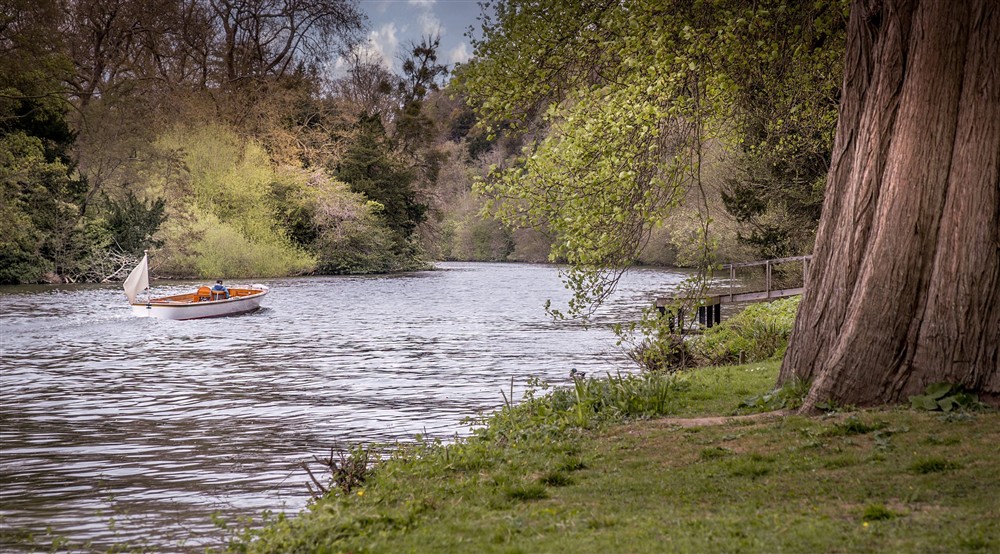 A boat travelling on the River Thames at Cliveden New Cottage in Nr Maidenhead, Berkshire