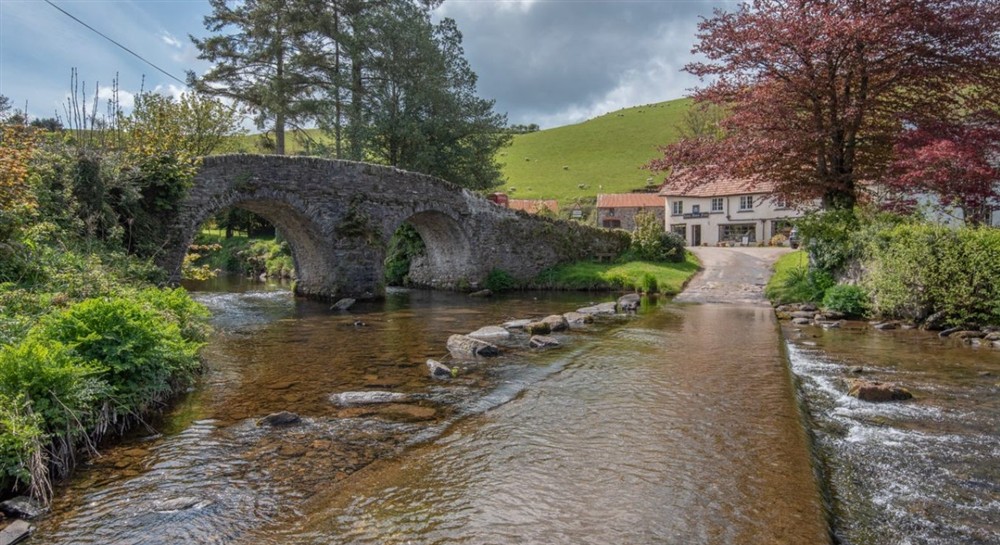 A stone bridge and ford surrounded by grassy hills and trees at Cloud Farmhouse in Lynton, Devon