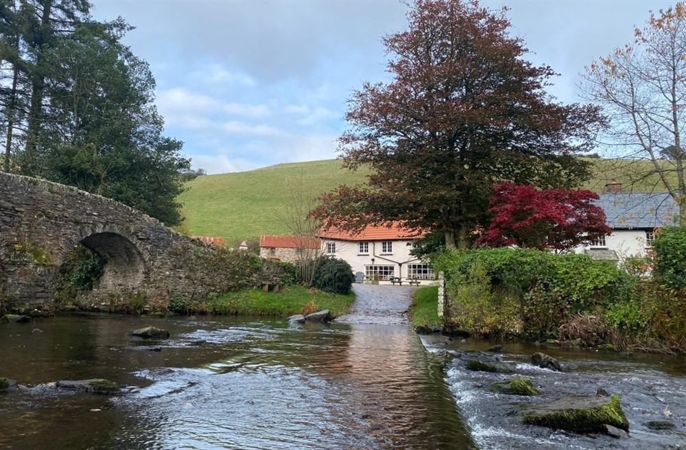 Looking across a ford surround by trees with an old stone bridge on the left hand side at Cloud Farmhouse in Lynton, Devon