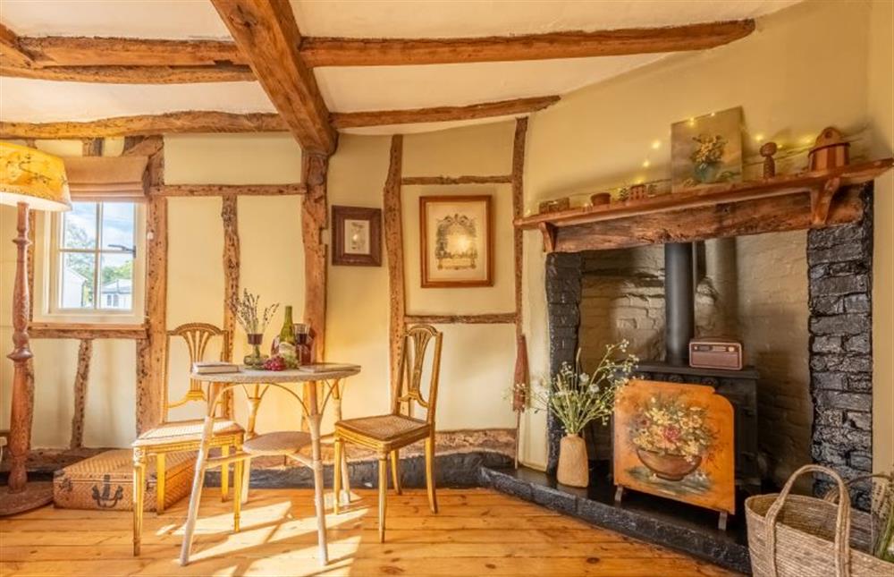 Sitting room with dining table and ornate fireplace at Cloudberry Cottage, Coddenham