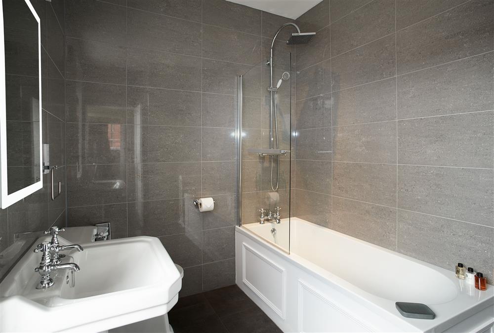 Bathroom with bath and overhead shower at Coach House, Netherby Hall, Longtown